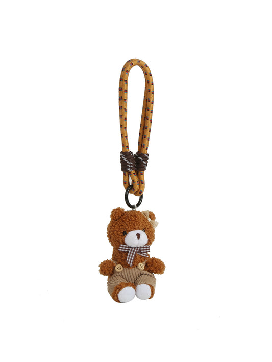 The HR Brown Bear Button Overalls Keychain features a small teddy bear plush with a brown and beige body, button accents, plaid bow tie, corduroy overalls, and a yellow strap with purple stitching on a plain white background.