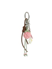 The HR Sweet Berry Blossom Crochet Keychain is a playful bag accessory featuring pink and cream crocheted flowers, a brown leather cord, green and white beaded string, and metal chain accents.