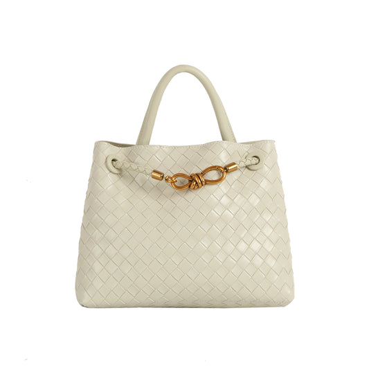 The LM Knot Accent Woven Tote is a cream-colored faux leather bag featuring two handles, a braided crossbody strap, and a gold-tone knot accent on the front.